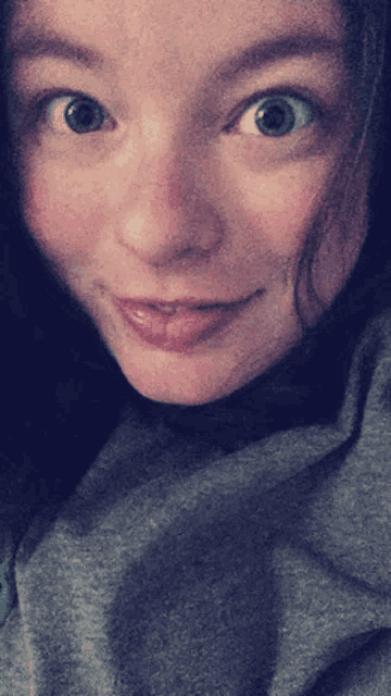 a close up of a woman 's face with a gray shirt