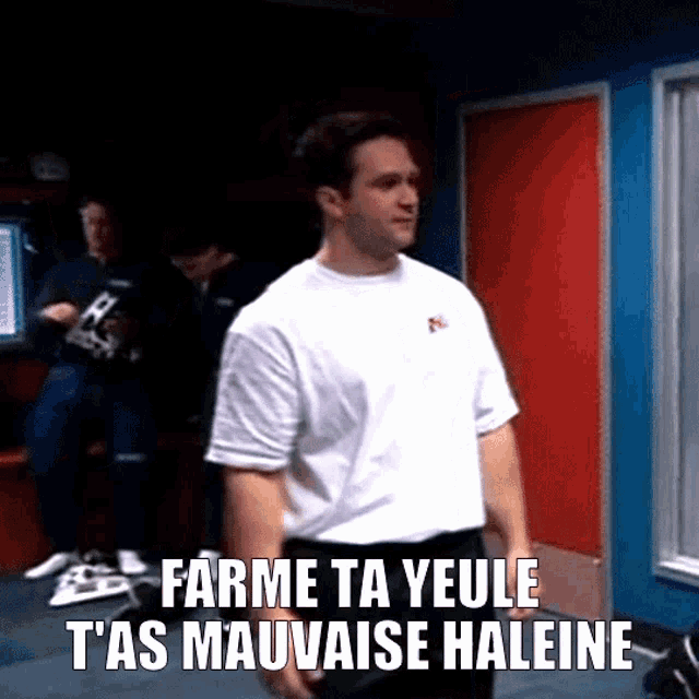 a man in a white shirt is standing in a room with the words farme ta yeule t'as mauvaise haleine above him