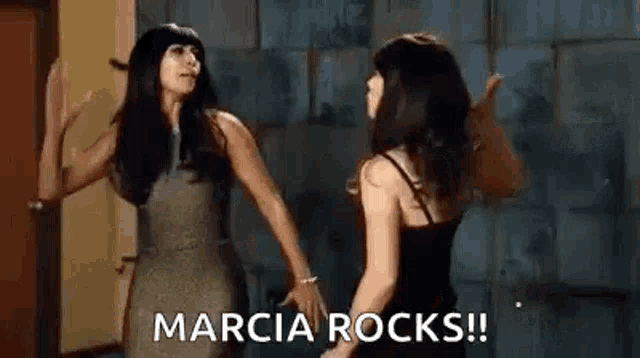 two women are standing next to each other in a room and one of them is shouting marcia rocks .