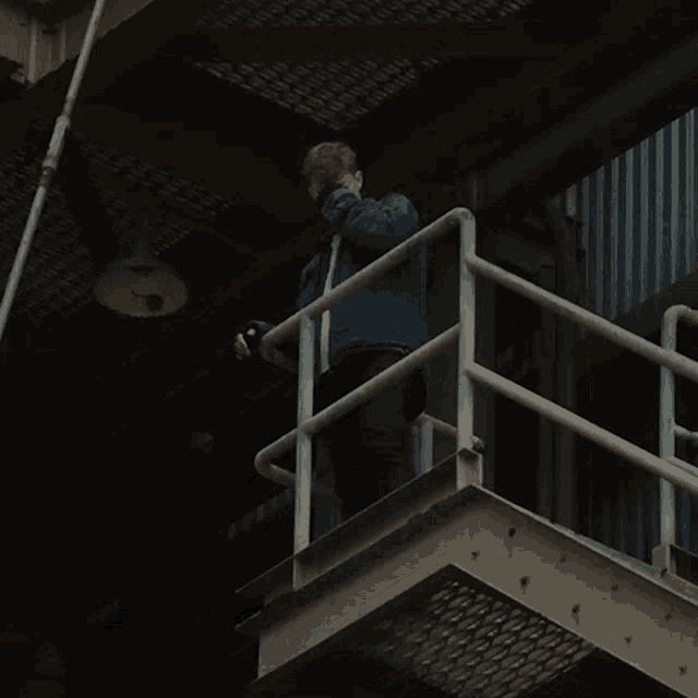 a man in a blue jacket is standing on a staircase