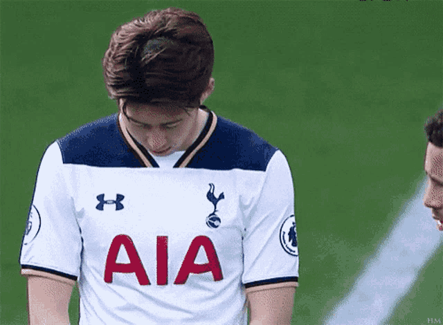 a young man wearing a white aia jersey looks down