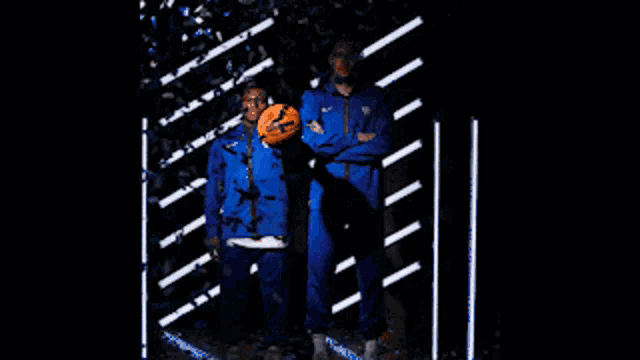 a man in a blue jacket holds a wilson basketball