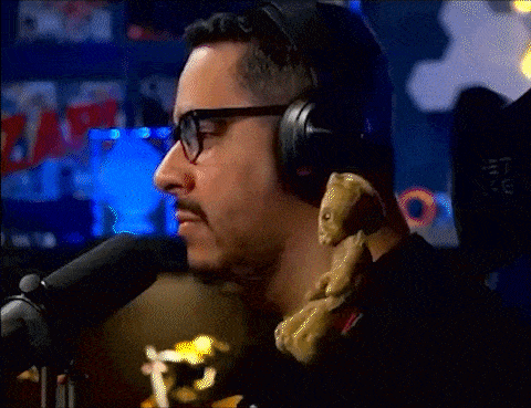a man wearing glasses and headphones is holding a teddy bear in front of a microphone