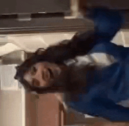 a woman in a blue shirt is standing in front of a refrigerator .
