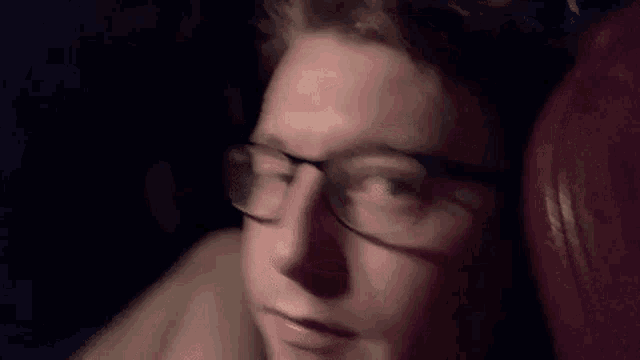 a close up of a person wearing glasses with a red background