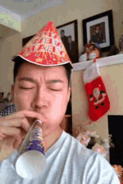 a man wearing a birthday hat blows a party horn