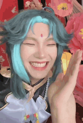 a woman with blue hair and a red bindi on her forehead smiles
