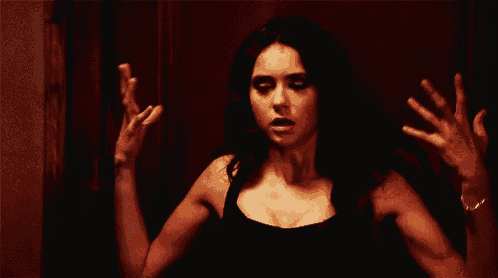 a woman is standing in front of a red door with her hands outstretched .