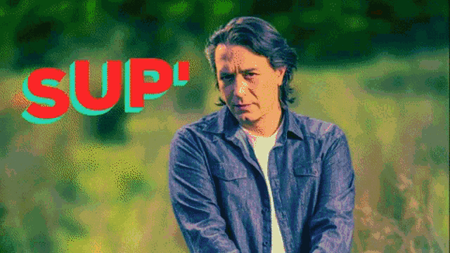 a man stands in a field with the word sup written in red