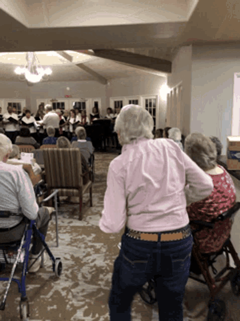 a woman in a pink shirt is dancing in front of a group of people