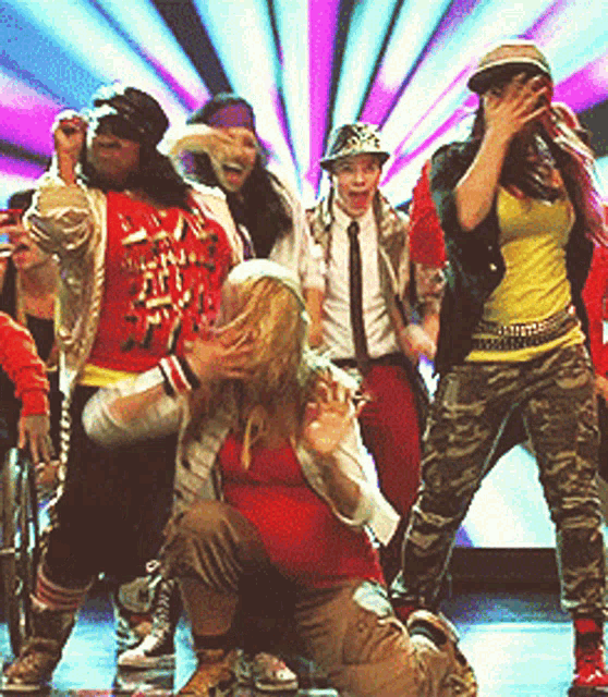 a group of people are dancing on a stage and one woman is wearing a red shirt that says ' i love you '