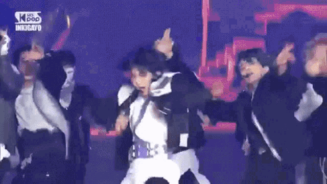 a group of people are dancing on a stage while a man holds a microphone .