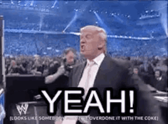 a man in a suit and tie is standing in front of a crowd and yelling .