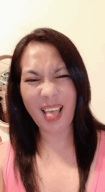 a woman in a pink tank top making a funny face