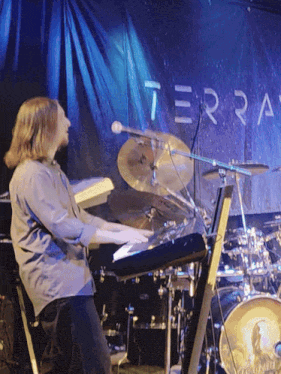 a man is playing a keyboard in front of a sign that says terra