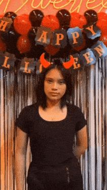 a girl in a black shirt is standing in front of a halloween decoration