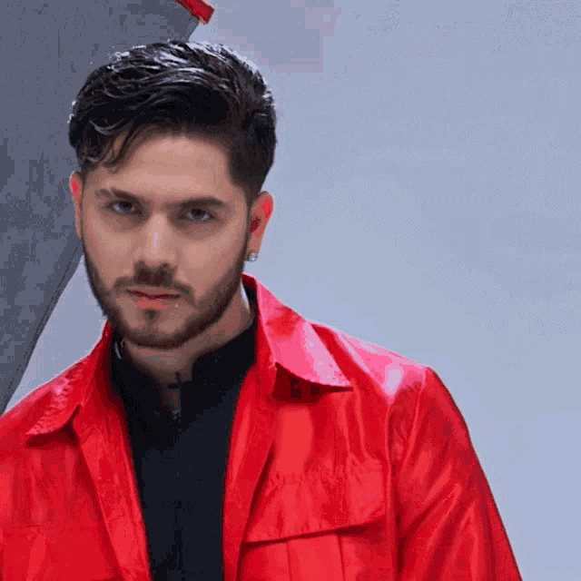 a man with a beard is wearing a red jacket and black shirt