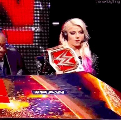 a woman wearing headphones is holding a wrestling championship belt .