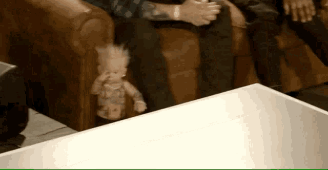 a doll with a mohawk is sitting on a table next to a group of people