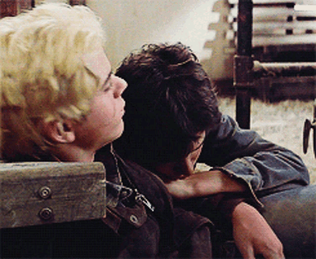 a man with blonde hair is hugging another man in a black jacket