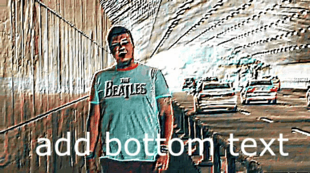a man wearing a beatles shirt is standing on a highway