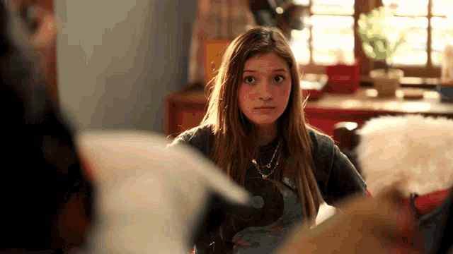 a girl with a necklace around her neck is sitting at a table