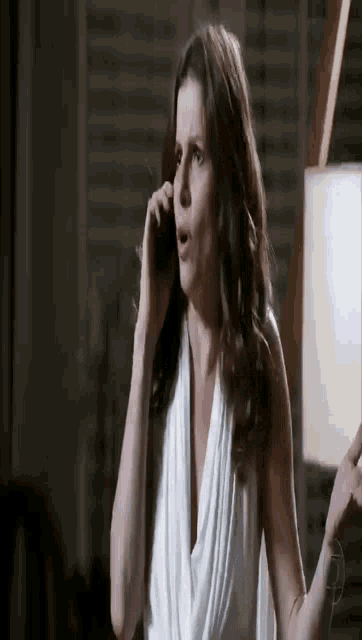 a woman in a white dress is talking on her cell phone .