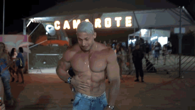 a shirtless man is standing in front of a sign that says cavarrote