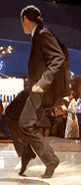 a man in a black suit is dancing on a dance floor