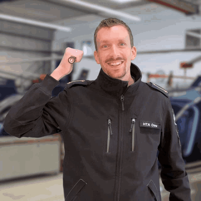a man wearing a black jacket with hta crew written on it
