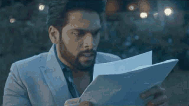 a man with a beard is holding a piece of paper in his hands .