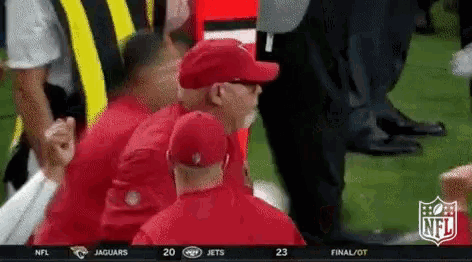 a group of men are watching a football game with the nfl logo on the screen