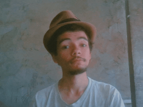a young man wearing a hat and a white shirt