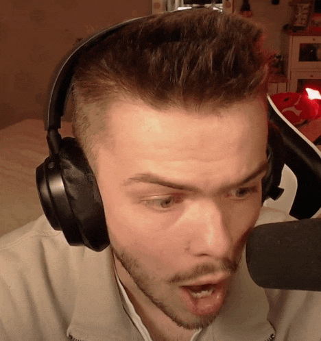 a man wearing headphones talks into a microphone with his mouth wide open