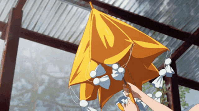 a person is holding a yellow umbrella with white ribbons