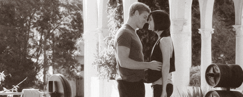 a black and white photo of a man and woman standing next to each other