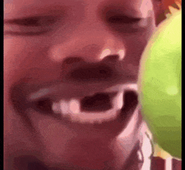 a close up of a person 's face with a green apple in his mouth .