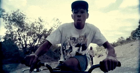 a young man wearing a cat shirt is riding a bike