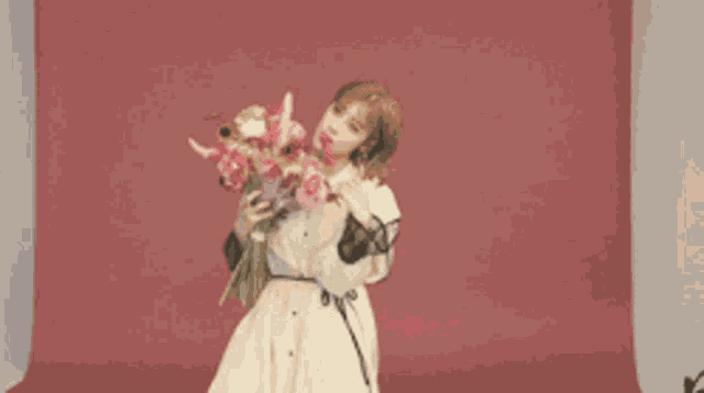 a woman in a white dress is holding a bouquet of flowers in front of a red backdrop