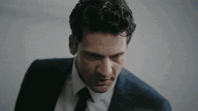 a close up of a man in a suit and tie looking at the camera .