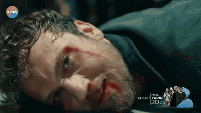a man with blood on his face is laying on the ground with show written on the bottom