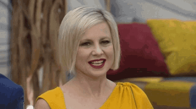 a woman in a yellow dress is smiling and looking at the camera
