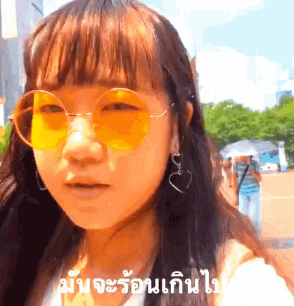 a girl wearing yellow sunglasses and earrings is making a funny face