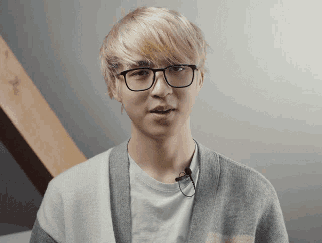 a young man wearing glasses and a gray sweater