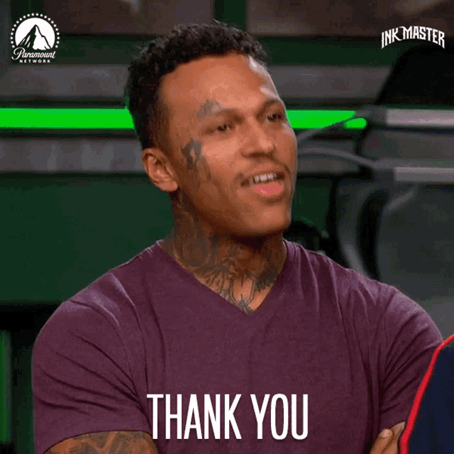 a man wearing a purple shirt with the words thank you on it