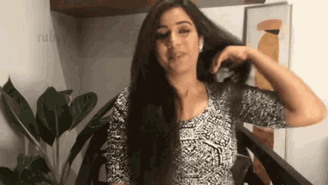 a woman in a black and white shirt is holding her hair