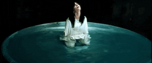 a woman in a white dress is kneeling in a circle of water