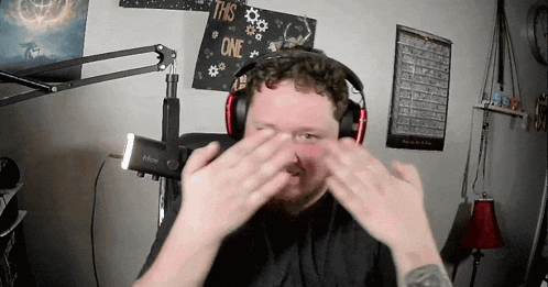 a man wearing headphones is making a funny face in front of a sign that says " this one "