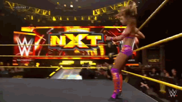 a woman in a wrestling ring with a sign that says nxt on it