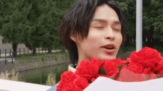 a young man is holding a bouquet of red roses